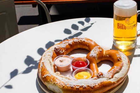 a pretzel on a plate with three dips