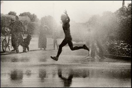 A man running through water in a race with his hands stretched in joy.