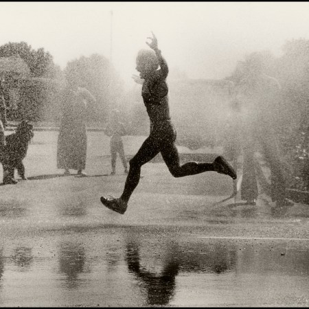 A man running through water in a race with his hands stretched in joy.