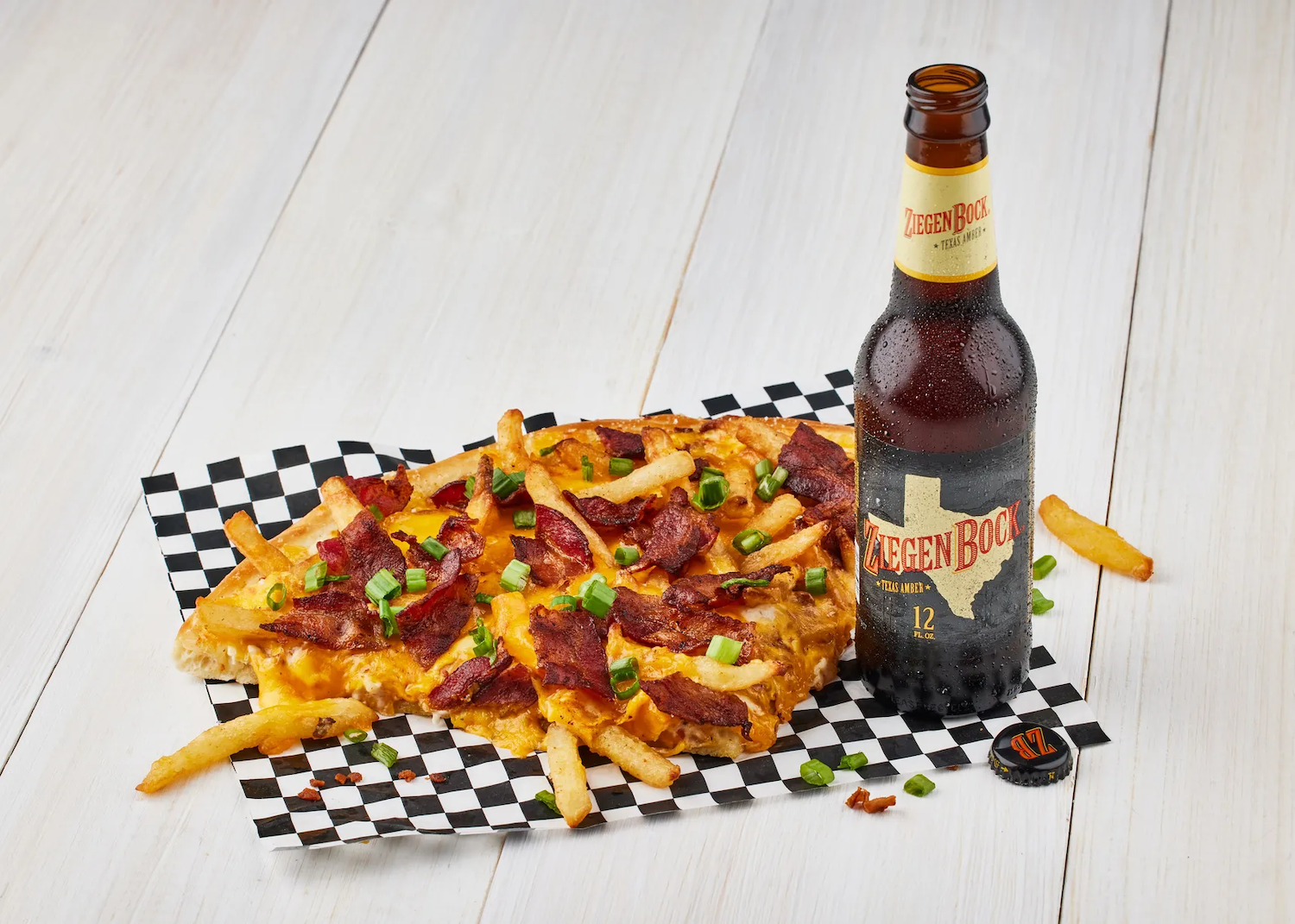 Loaded fries pizza next to beer bottle