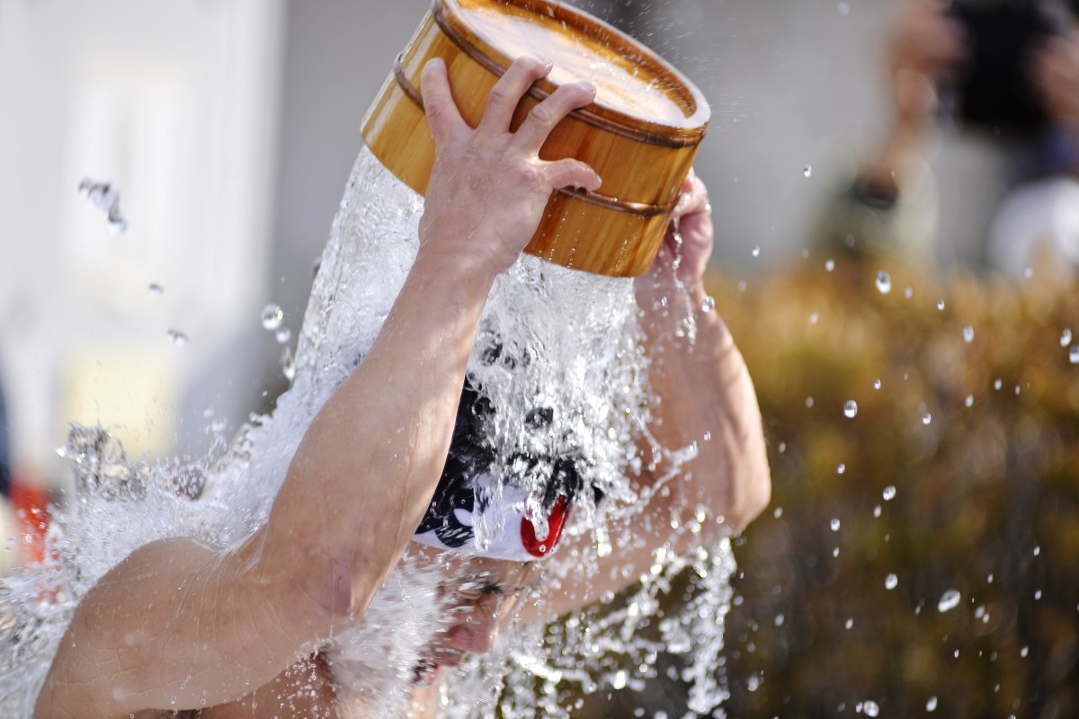 A man pours cold water on his head from a bucket.