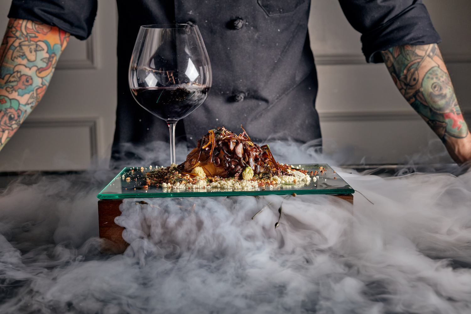 Surf and turf next to a glass of wine surrounded in smoke