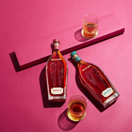 The new 2023 Cask Strength releases from Angel's Envy, with two glasses, lying on a pink tabletop