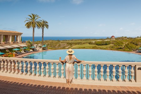 Woman standing on a terrace looking over the Coliseum Pool at the Resort at Pelican Hill