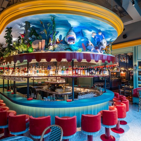 Blue and red bar area with neon colors and dim lighting with scenic ocean design on top of the bar