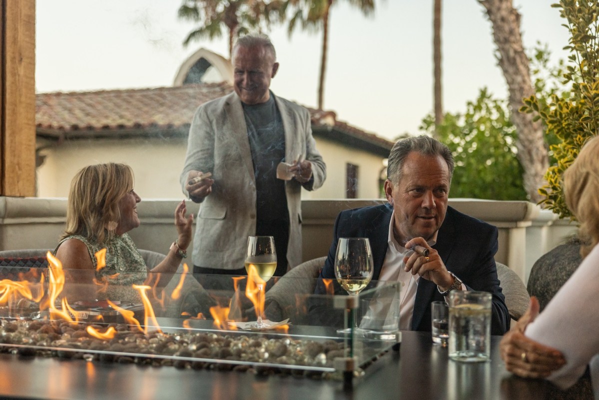 People sitting at a table fire with cigars in their hands