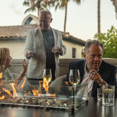 People sitting at a table fire with cigars in their hands