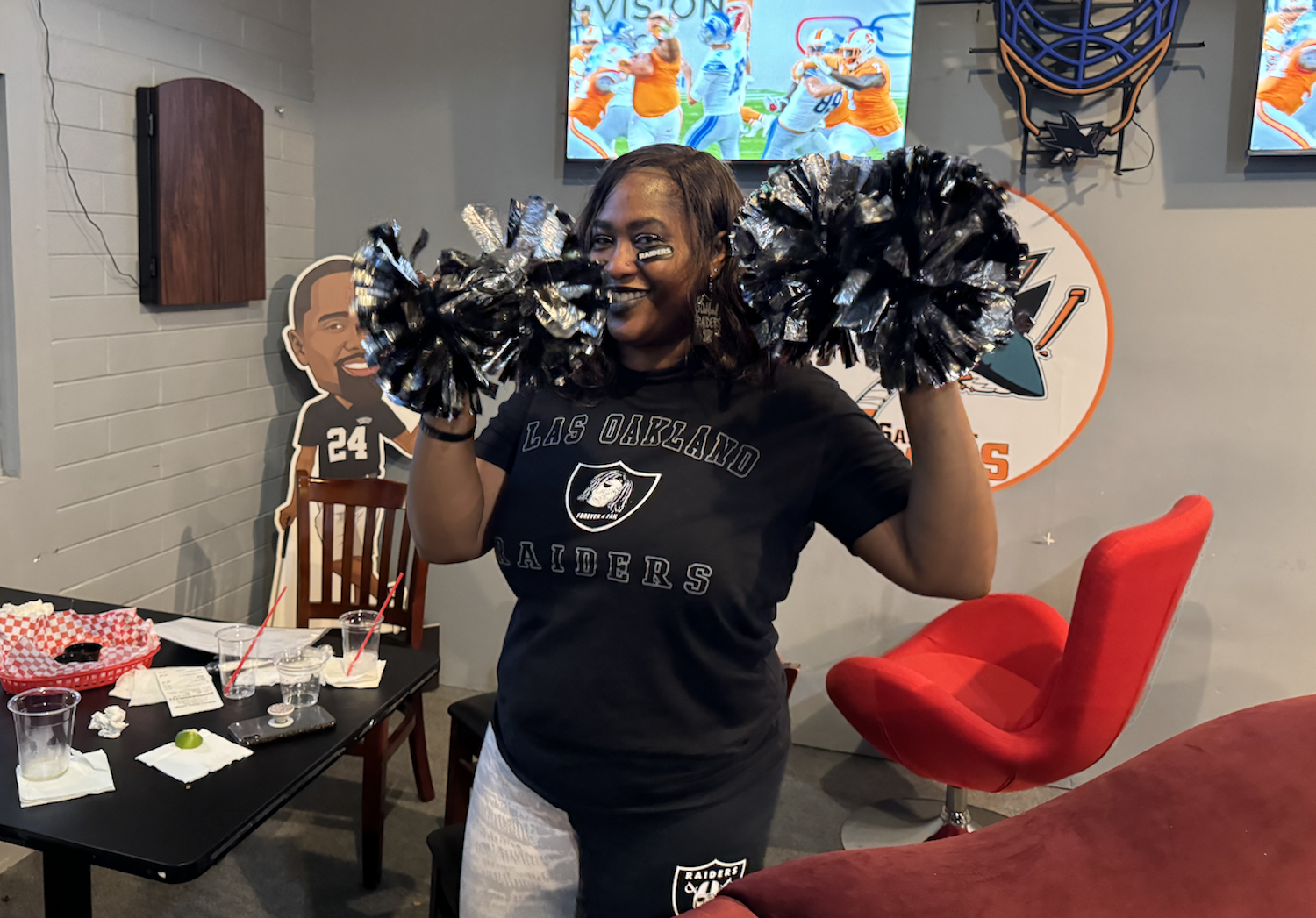 Fan with pom poms and Raiders merch at Rickeys