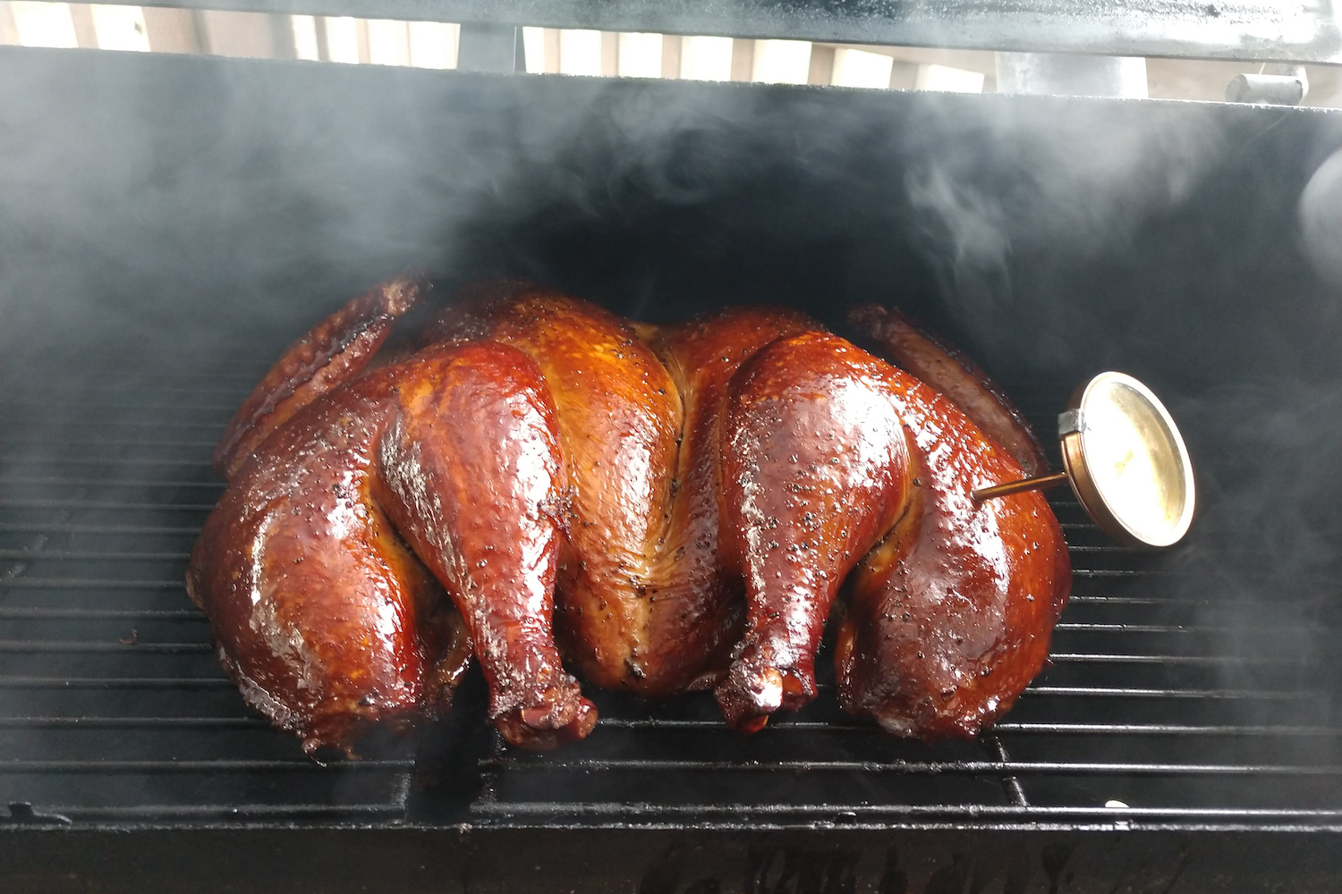 A glistening smoked turkey in a smoker