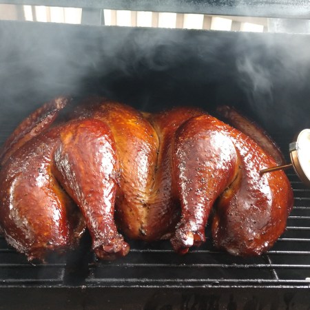 A glistening smoked turkey in a smoker