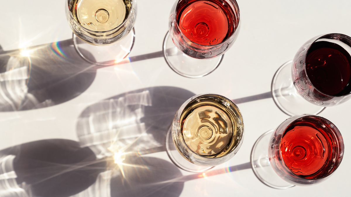 Red, rose and white wine top view in sunlight. Assorted wine in glass. Dark shadows