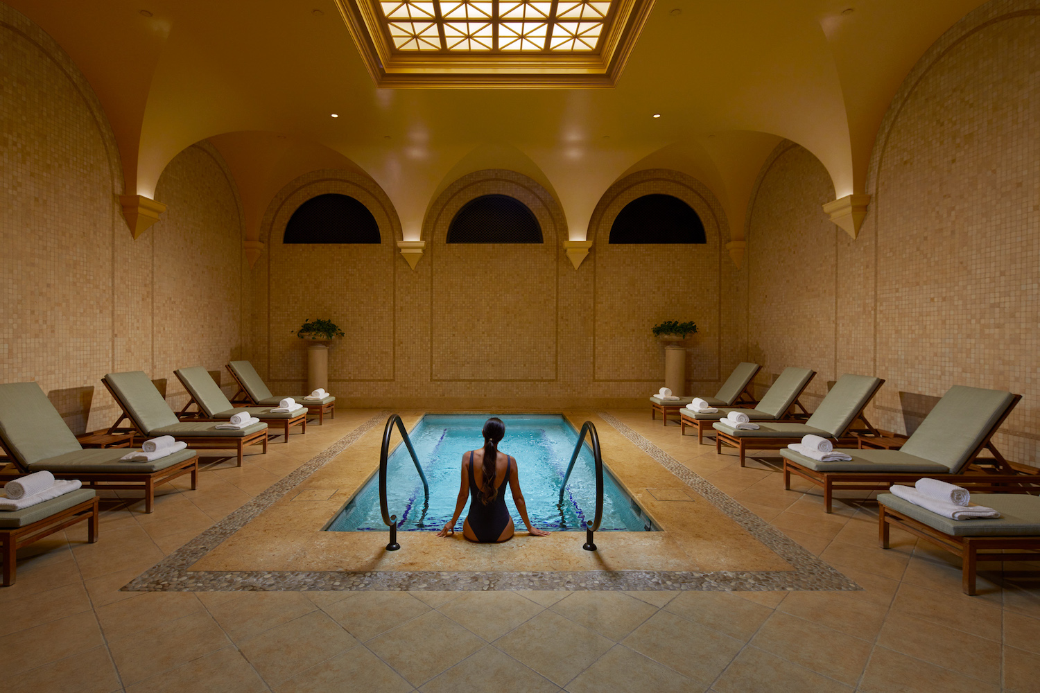 Woman sitting at the edge of indoor pool