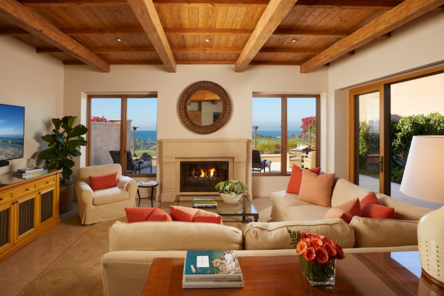 Brown-colored living room area with fireplace, red-orange accents and a view of the water