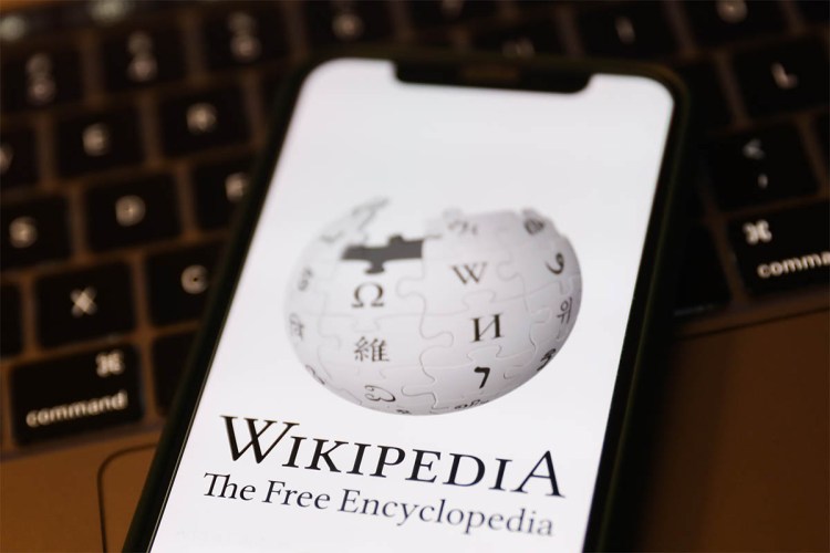 Wikipedia logo displayed on a phone screen and a laptop keyboard are seen in this illustration photo taken in Krakow, Poland on January 19, 2023. Elon Musk has questioned the need for donations to the site.