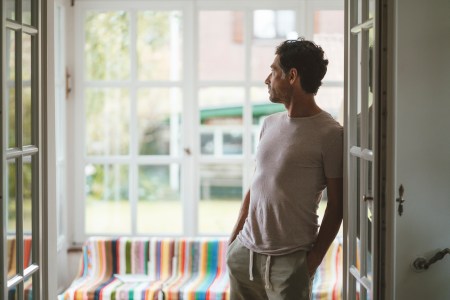 A man stretching in a doorway threshold in his house.