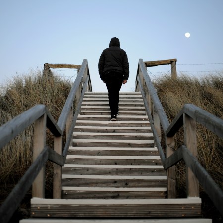 A man walks up the steps on a flight of stairs at a beach.