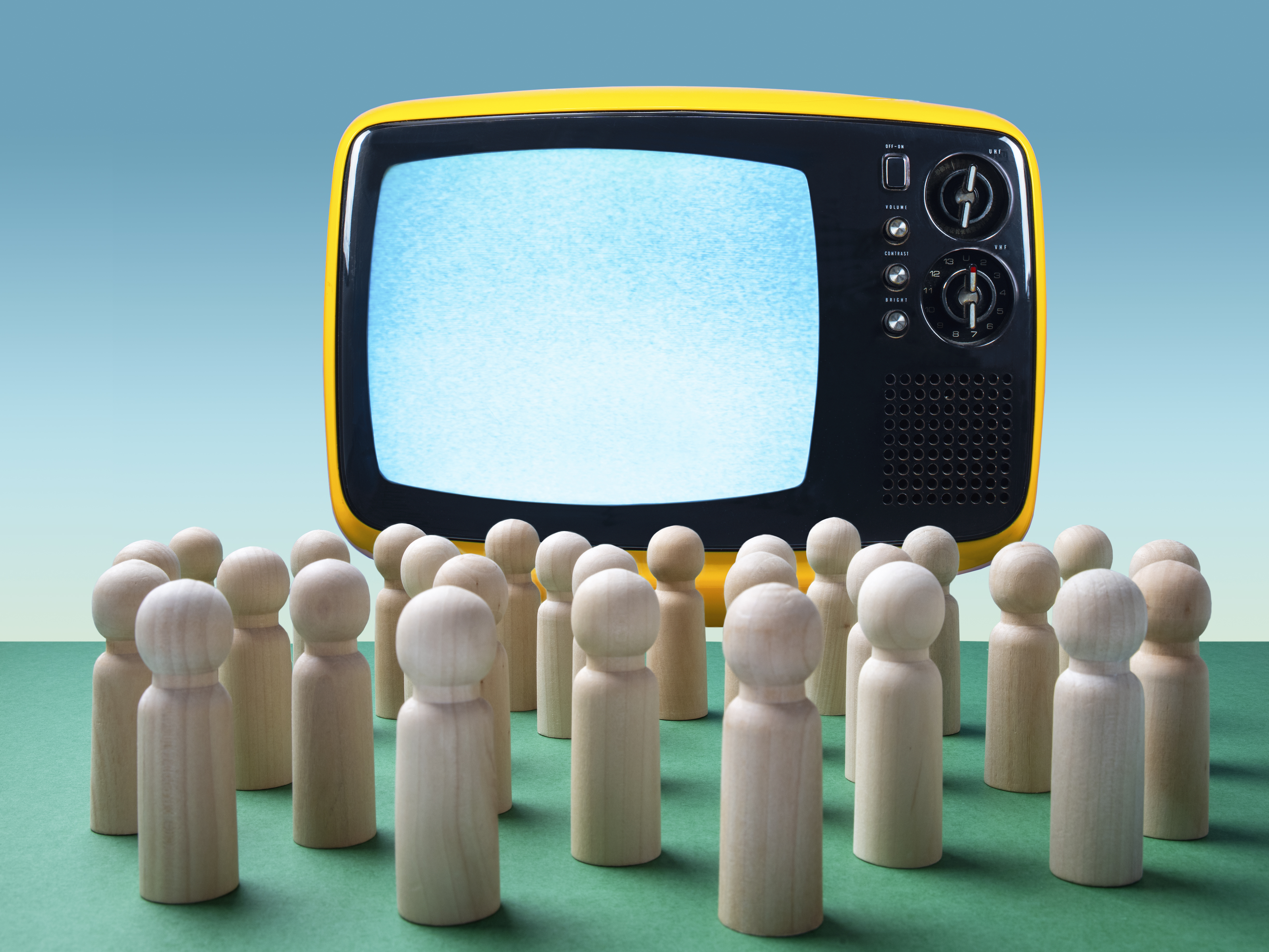 Wooden figurines facing an empty old-school television.