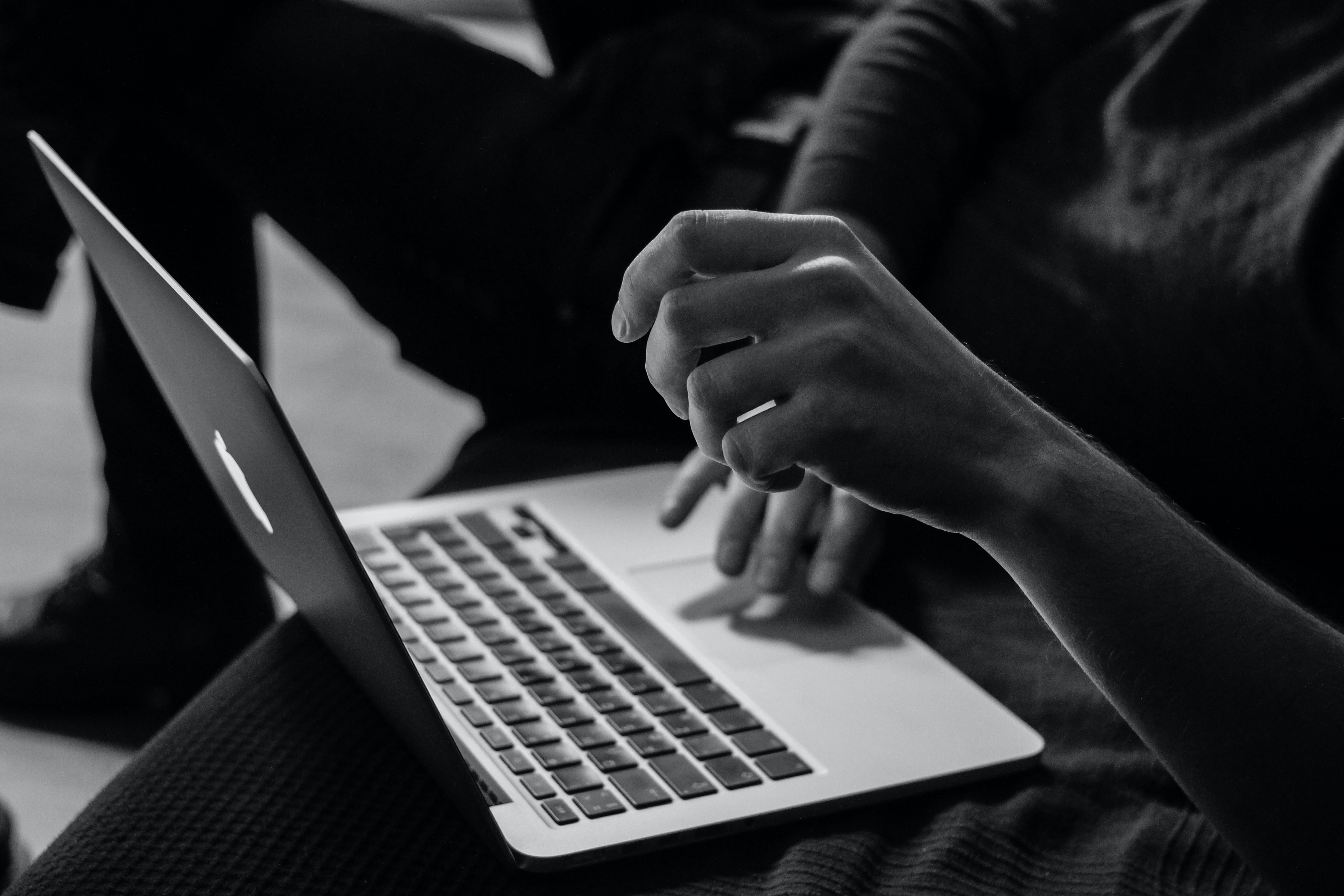 An employee typing at a laptop in black and white. Shallow work is interfering with productive "deep work."