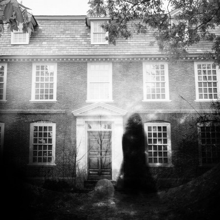 spooky black and white photo of a shadowy figure outside of an old house