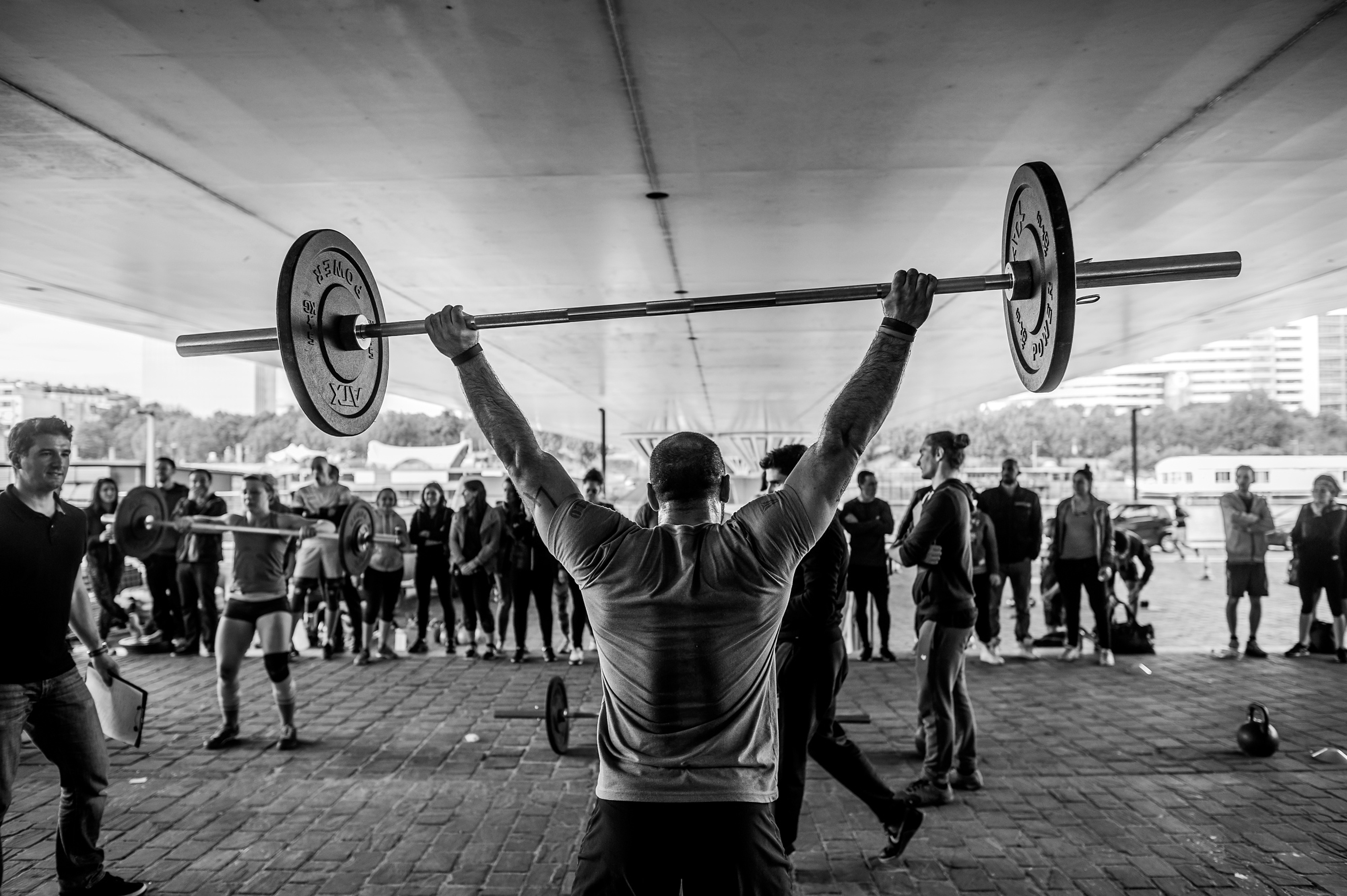 A workout class taking place outside under a bridge.