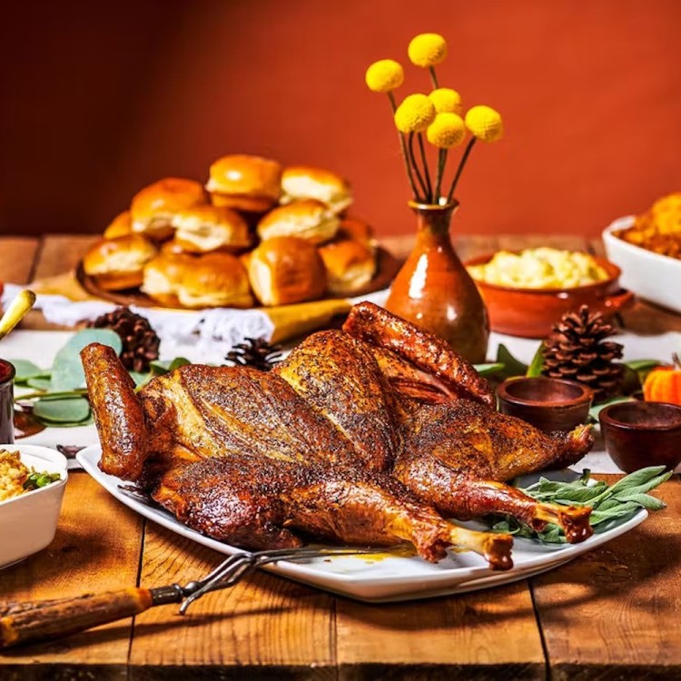 Spread of thanksgiving sides surrounded by a cooked turkey on a table