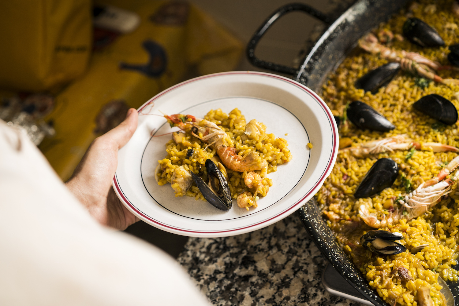 Person serving seafood paella on a plate