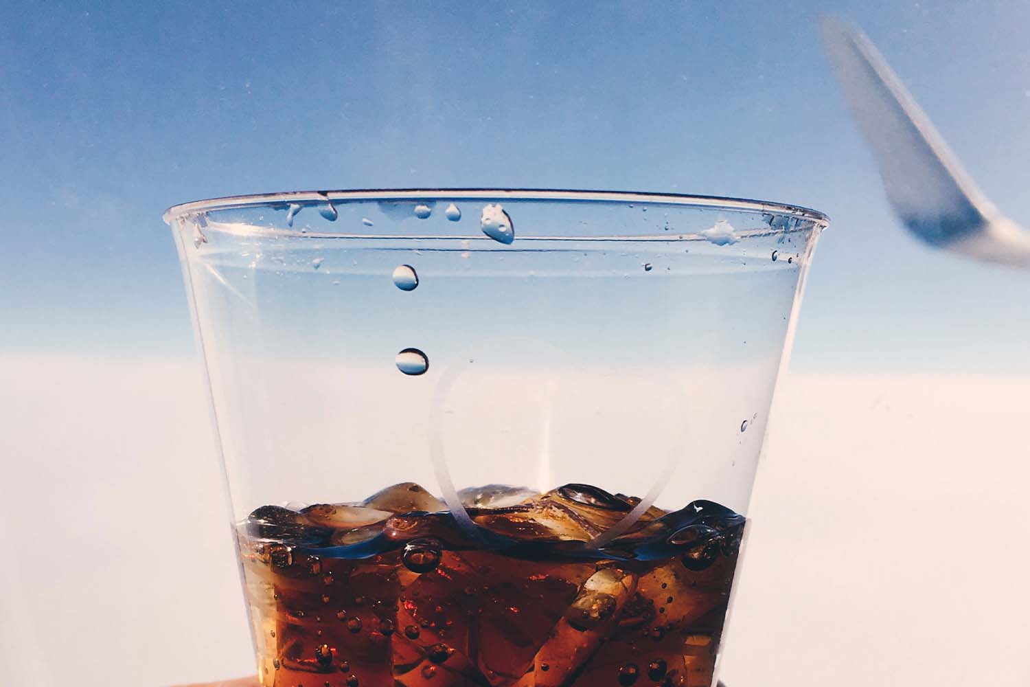 An airplane plastic cup with a Coke-based cocktail in it. We look at the best cocktails to drink on an airplane.