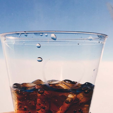 An airplane plastic cup with a Coke-based cocktail in it. We look at the best cocktails to drink on an airplane.