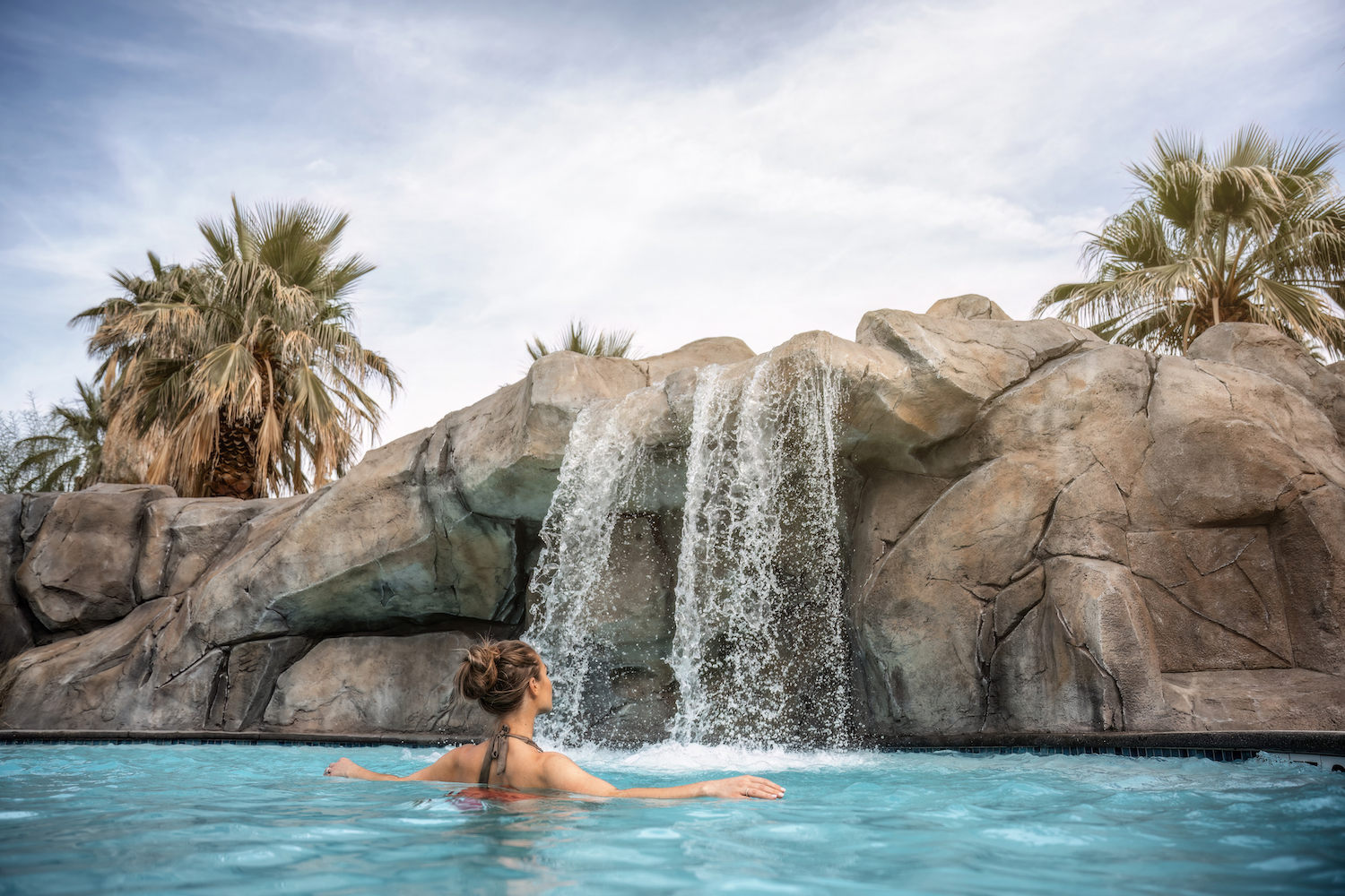 Lady in a pool looking at water fixture