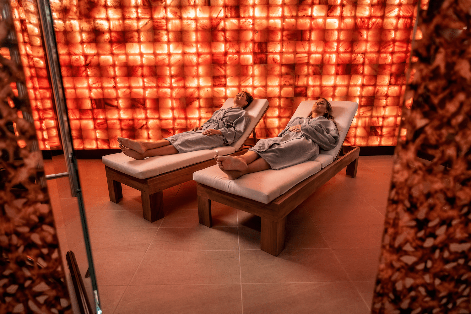 Two people laying in room with walls made of salt 