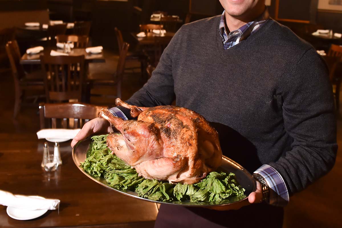 Hitching Post co-owner George Zeppos poses for a photo with one of the turkeys that his restaurant has prepared in advance of Thanksgiving. At The Hitching Post restaurant in Bern Township Tuesday evening November 21, 2017