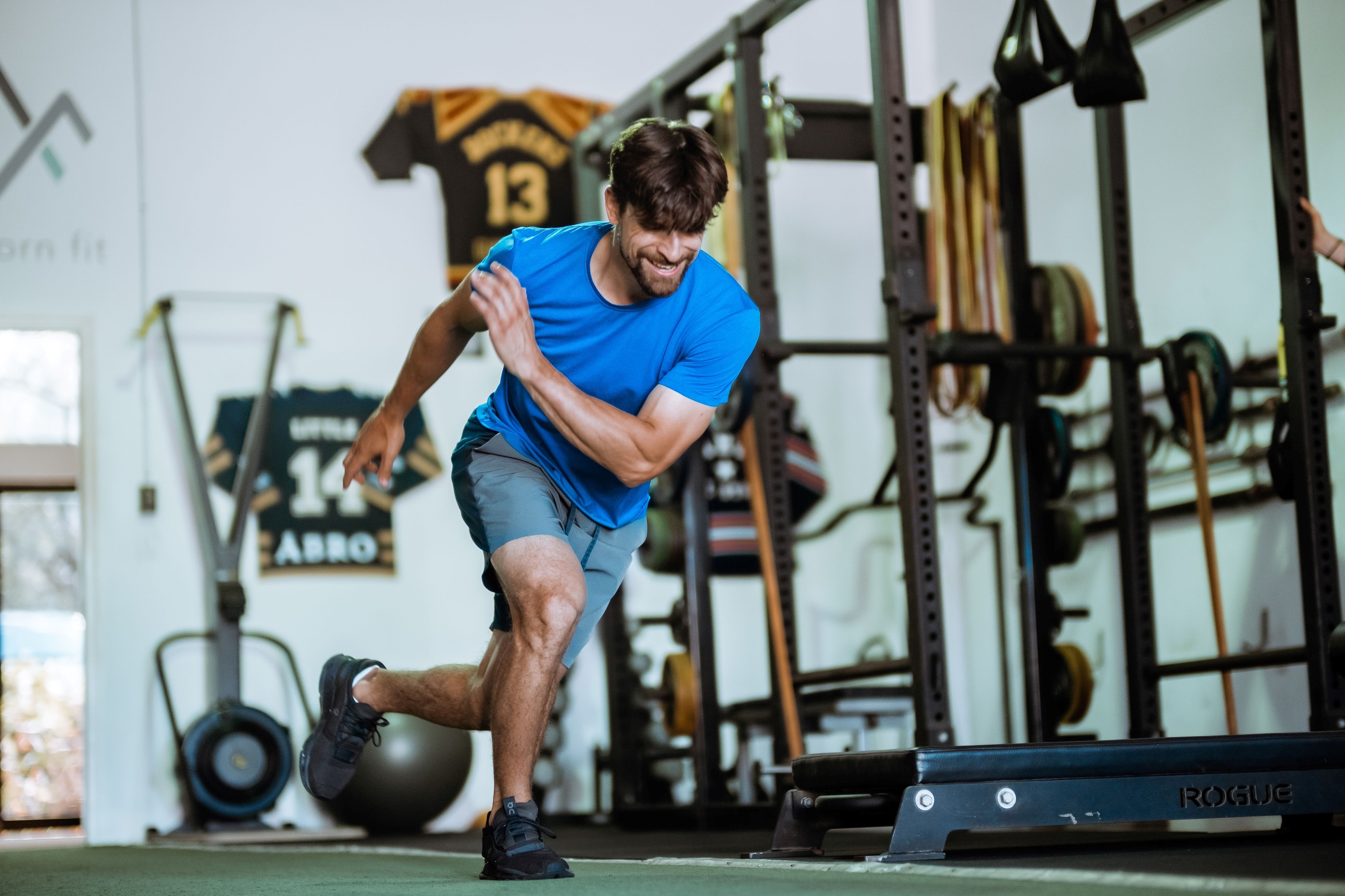 A man lunging across a gym floor.