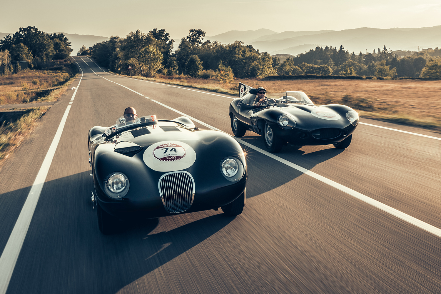 Jaguar Classic C-type and D-type driving on a rural road in Italy