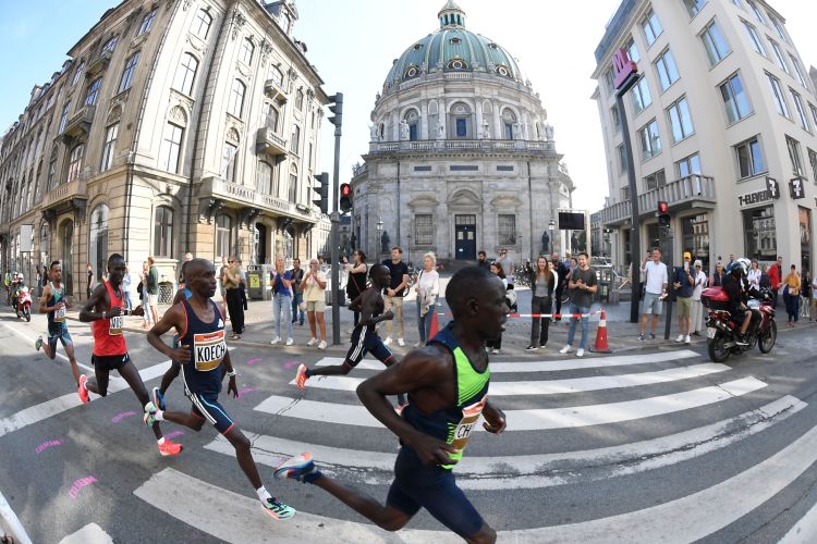 A crew of runners racing past a church in Copenhagen.