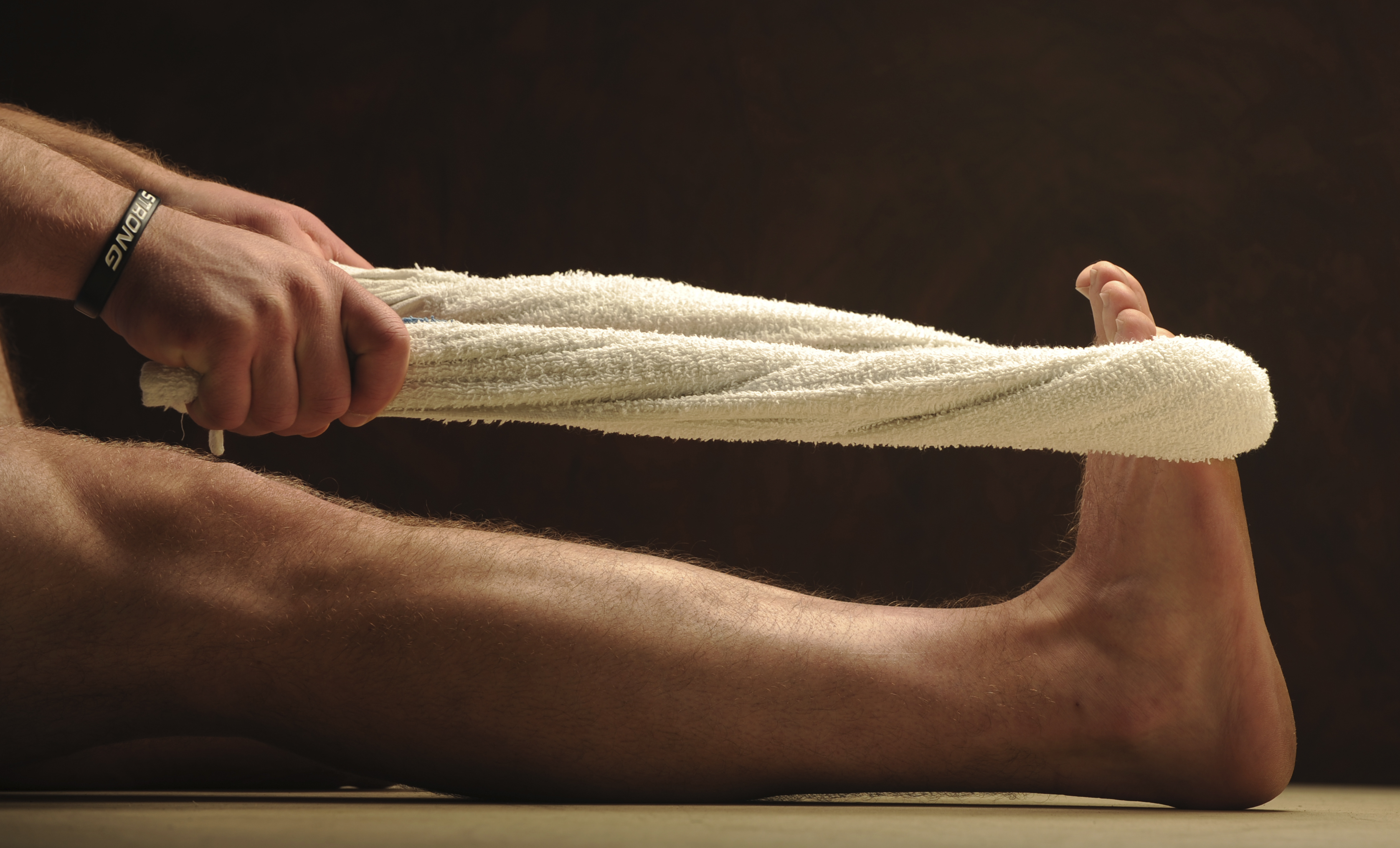 A person stretching their legs with a towel. Working out with a towel is surprisingly effective.