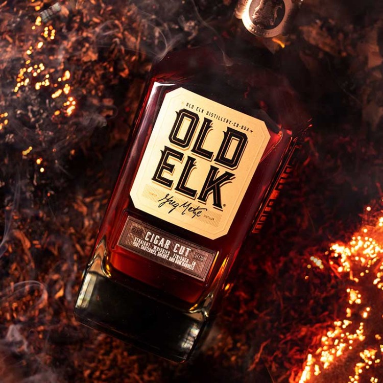 A bottle of Old Elk Cigar Cut on a pile of tobacco and cigars. Cigar cut or cigar blends are becoming popular in whiskey.