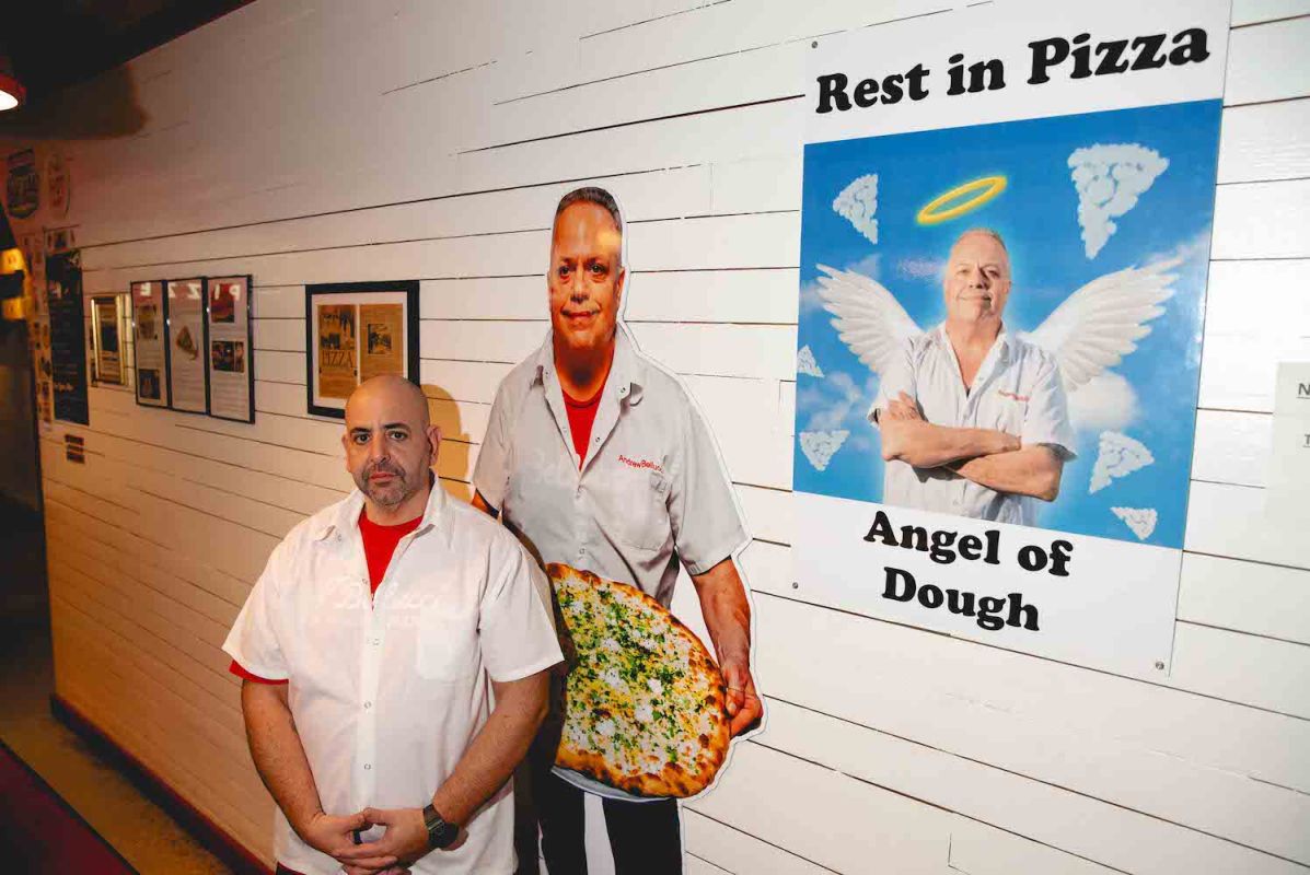 Matthew Katakis stands next to a lifesize photo of his former chef and business parter at his Astoria pizzeria
