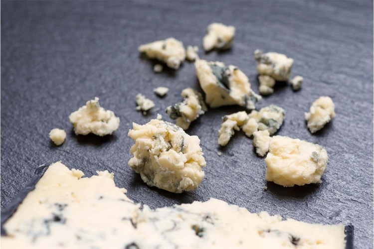 top view of tasty pieces cheese with blue mold on black slate background. An Oregon brewery just made a beer out of blue cheese.