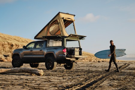 The Super Pacific X1, a truck canopy camper, in the bed of a pickup sitting on the beach