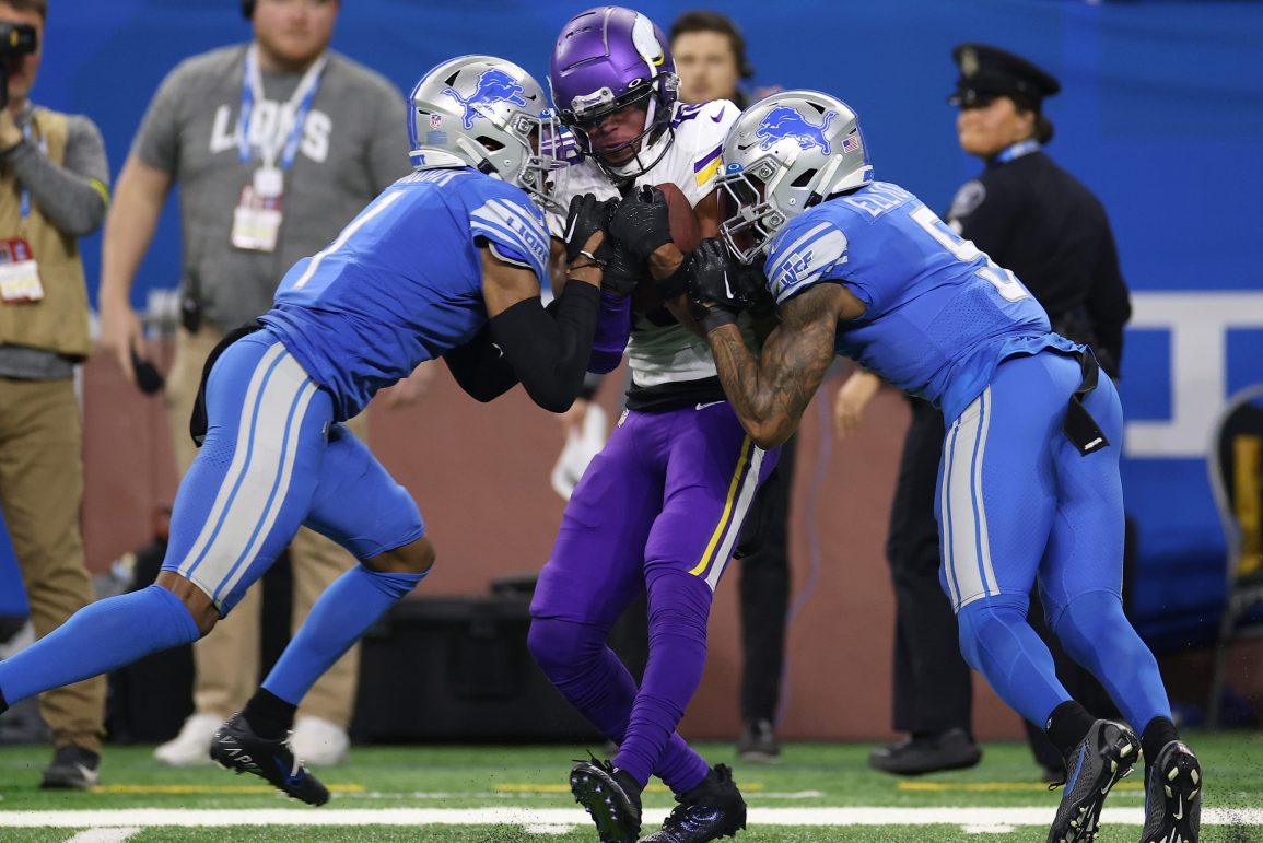 Justin Jefferson of the Vikings is tackled by two Detroit Lions.