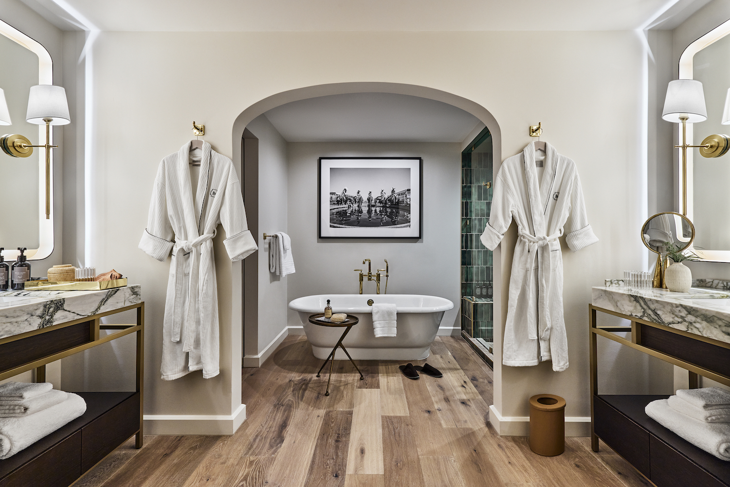 Luxury bathroom with wide bathtub, white robes and other accompanying bathroom wellness supplies