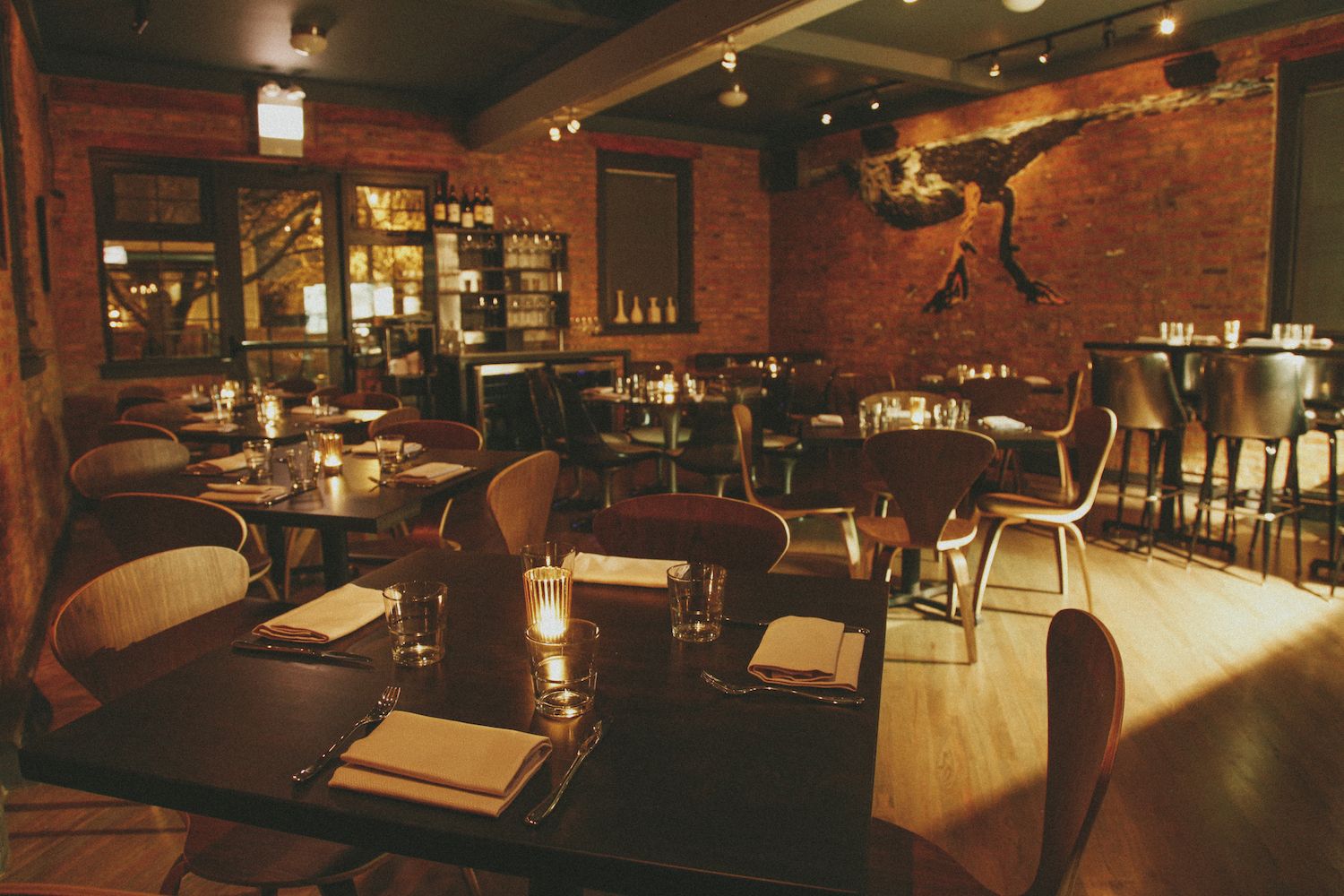 Dim-lit dining room with dark-colored seating and decorated brick walls