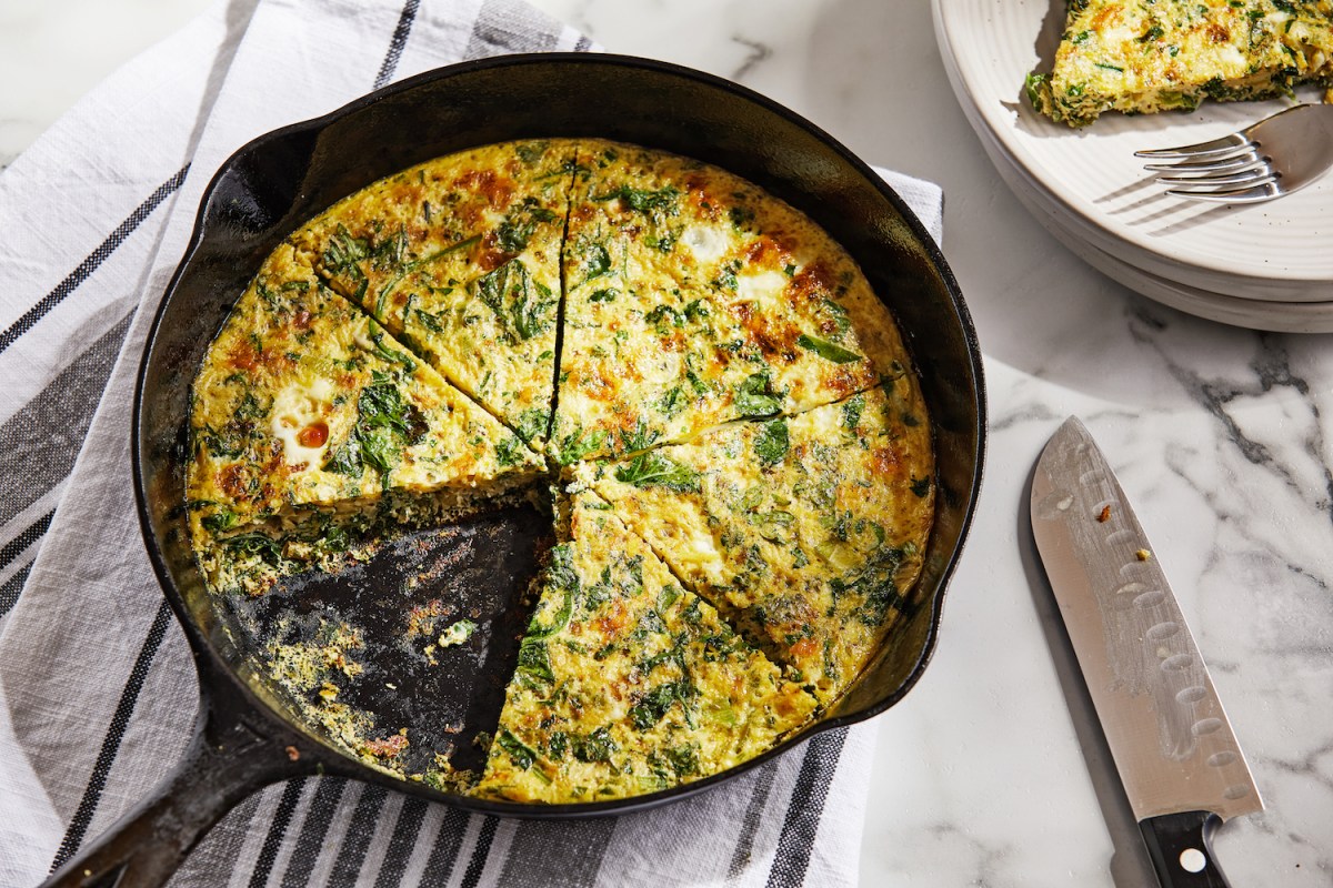 veggie frittata in a cast iron skillet with a slice cut out