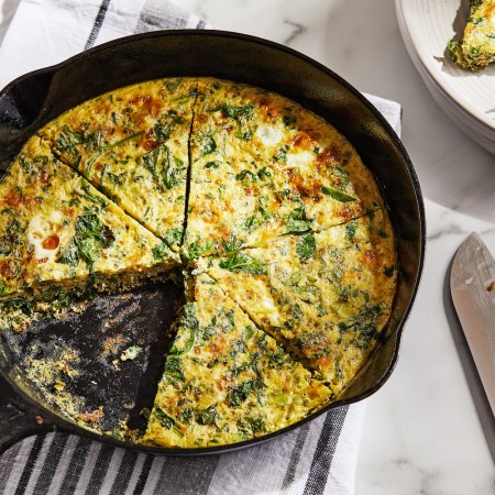 veggie frittata in a cast iron skillet with a slice cut out