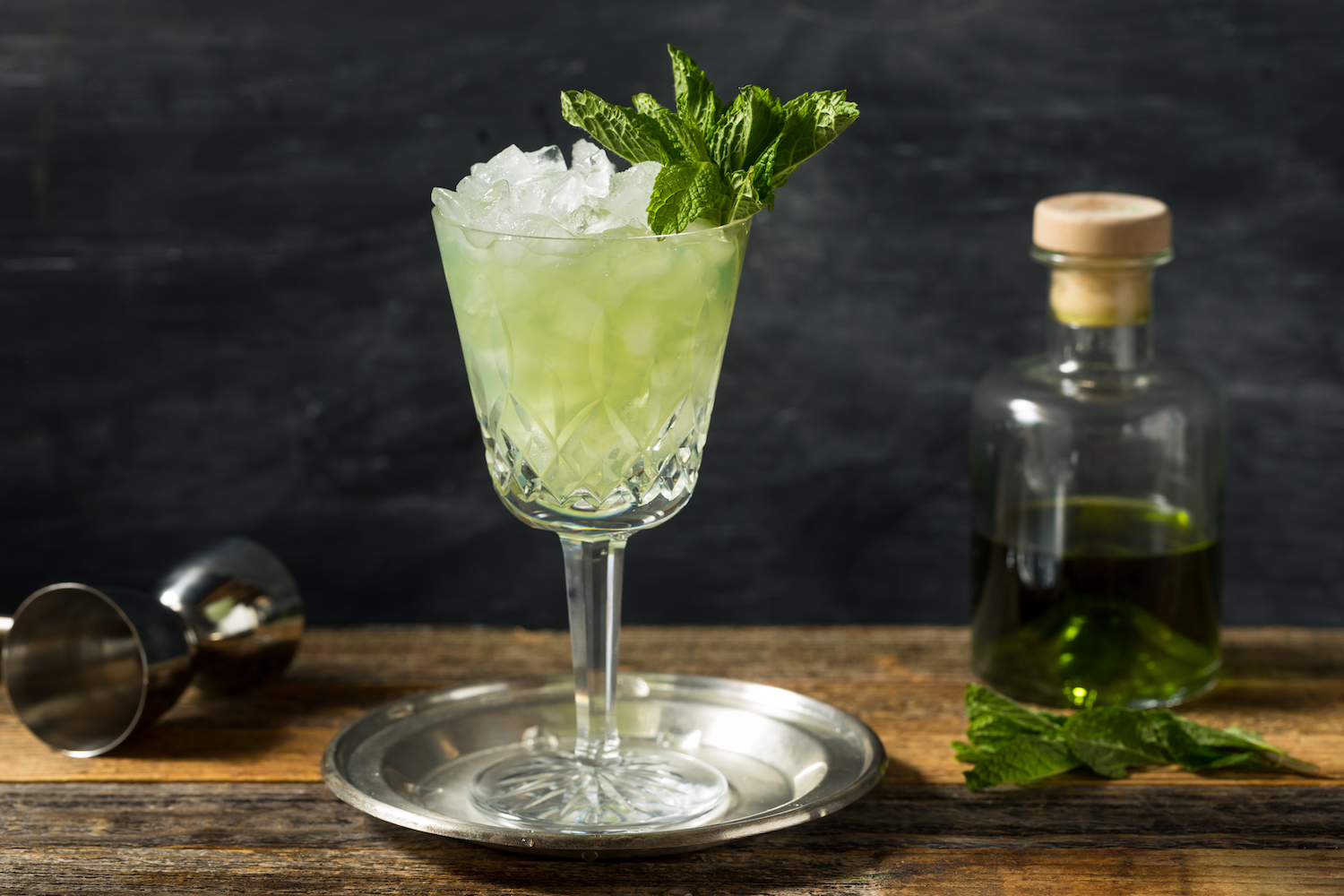 absinthe frappe cocktail garnished with mint on a silver coaster