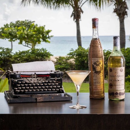 The E Hemingway Cocktail, vintage rums and a typewriter in front of Library by the Sea in Grand Cayman