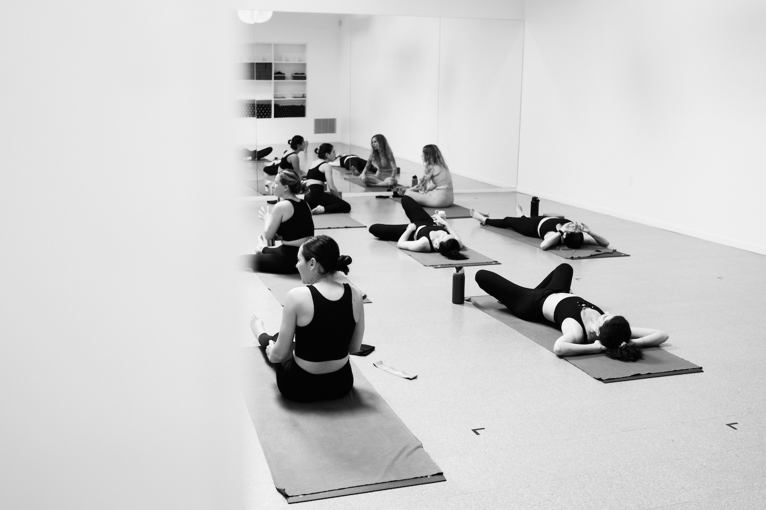 Group of women laying on mats in a fitness studio 