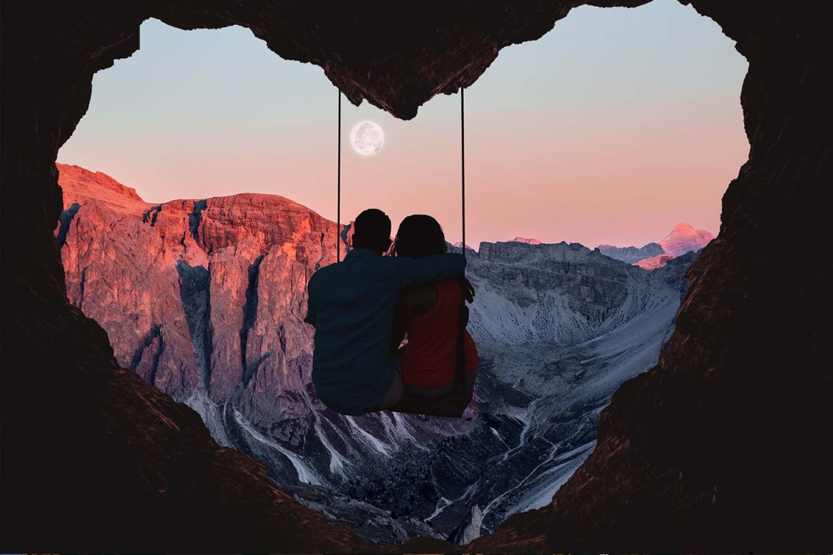 A couple sitting i a cave outpost on a mountain that looks like a heartr. It's not always rainbows and butterflies when you travel with a partner.