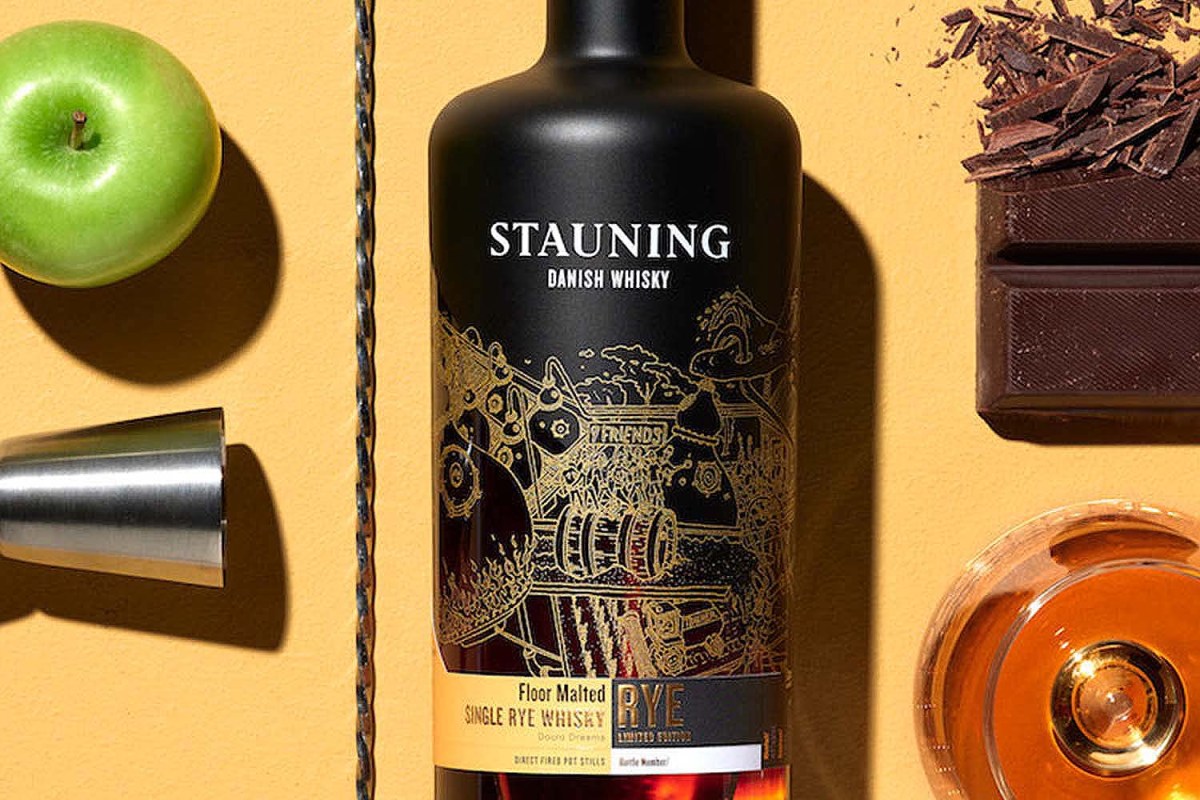 Stauning, a Danish rye whiskey, on a table with whisky, chocolate, a jigger and an apple. Stauning is one of several whisky brands around the globe offering rye.