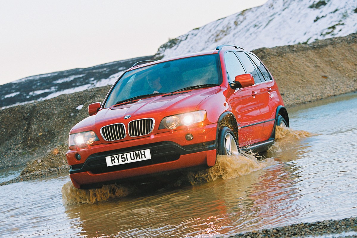 An early BMW X5 driving through deep water in the wilderness. We take a look at the history of the BMW X series.